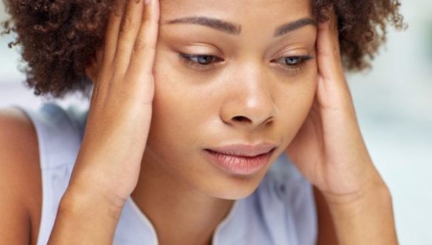 people, emotions, stress and health care concept - unhappy african american young woman touching her head and suffering from headache